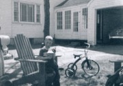 1955-05-01~ 3 Dan with new bell, tricycle, and Mom's original green coupe in garage (HBD Dad & Dan).jpg